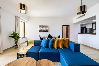 a blue couch with yellow pillows in a living room at Amazing 1BR With Sea View Rimal 4 JBR - NOX Holiday Homes in Dubai
