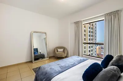 a bedroom with a bed and a mirror and a chair at Amazing 1BR With Sea View Rimal 4 JBR - NOX Holiday Homes in Dubai