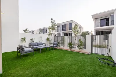 a patio with chairs and grass in a building at Townhouse with Garden I Tilal Al Ghaf I Elan B in Dubai