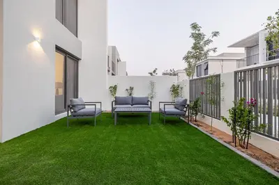 a patio with green grass and two chairs at Townhouse with Garden I Tilal Al Ghaf I Elan B in Dubai