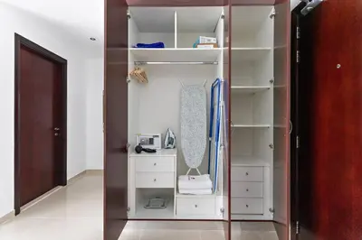 a closet with white shelves and a wooden door at StoneTree - Cozy Studio in DEC Tower - Dubai Marina in Dubai