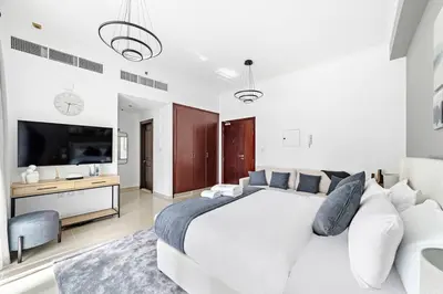 a white bedroom with a large bed and a television at StoneTree - Cozy Studio in DEC Tower - Dubai Marina in Dubai