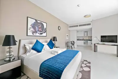 a bedroom with a large bed with a blue blanket at StoneTree - Stylish Studio Apartment in Damac Hills in Dubai