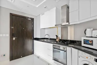 a kitchen with white cabinets and a stove top oven at StoneTree - Stylish Studio Apartment in Damac Hills in Dubai