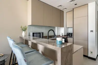 a kitchen with a counter with two blue chairs at GuestReady - Majestic canal and Burj Khalifa view in Dubai
