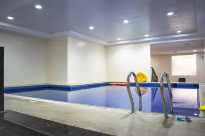 a swimming pool with twoadders in a room at Your Silicon Oasis Escape-1BHK in Dubai