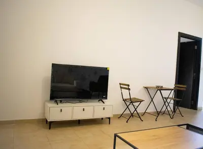 a living room with a flat screen tv on a white wall at Your Silicon Oasis Escape-1BHK in Dubai
