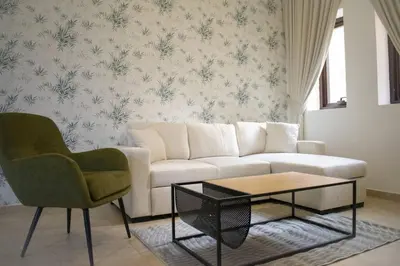 a living room with a white couch and two chairs at Your Silicon Oasis Escape-1BHK in Dubai