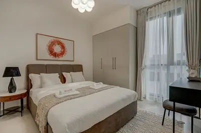 a bedroom with a large bed and a window at Brand New Luxurious 4BR & Maid Room Townhouse in Dubail Hill Estate in Dubai