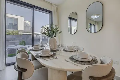 a dining room with a wooden table and chairs at Brand New Luxurious 4BR & Maid Room Townhouse in Dubail Hill Estate in Dubai