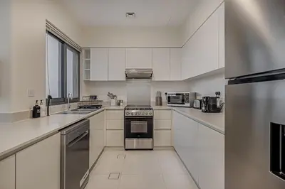 a kitchen with white cabinets and a stainless steel appliance at Brand New Luxurious 4BR & Maid Room Townhouse in Dubail Hill Estate in Dubai