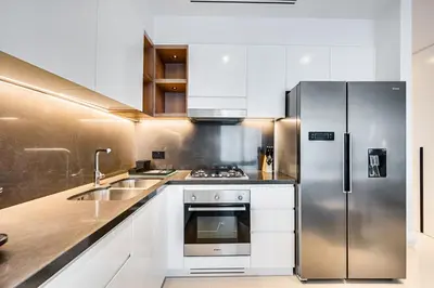a kitchen with white cabinets and a stainless steel refrigerator at Elegant 3BD family home in Marina Vida Residence in Dubai