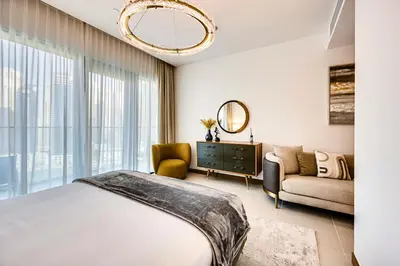 a bedroom with a bed and a couch and a chandelier at Elegant 3BD family home in Marina Vida Residence in Dubai
