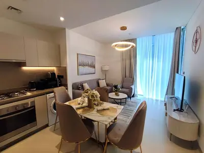 a kitchen and a living room with a table and chairs at New 1 bedroom in Sobha - Community View in Dubai