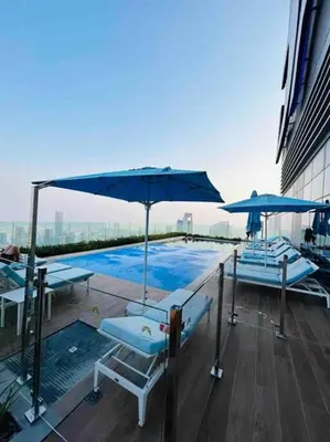 a pool with chairs and umbrellas on top of a building at Unique 2br with Infinity Pool view on Burj Khalifa in Dubai