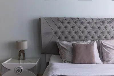 a bed with a silver headboard and a table with a lamp at Unique 2br with Infinity Pool view on Burj Khalifa in Dubai