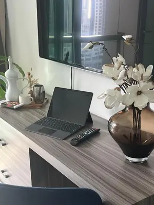 a desk with a laptop computer and a vase with flowers at 8 Boulevard Walk 'Heart of Downtown' in Dubai