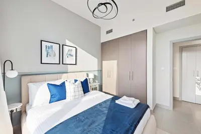 a bedroom with a bed with blue and white pillows at Silkhaus awesome 1BDR in Opera District in Dubai