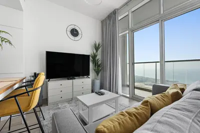 a living room with a couch and a tv and a table at StoneTree - Best Rate Studio in Dubai Marina in Dubai