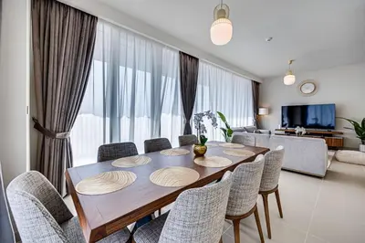 a dining table and chairs in a living room at Comfy family 3BD apartment in Dubai Creek Harbour in Dubai