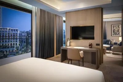 a hotel room with a bed and a desk with a large window at Palace Dubai Creek Harbour in Dubai