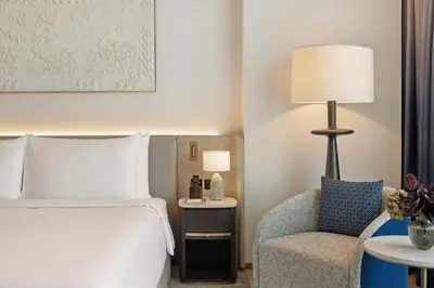a bedroom with a bed and a chair and a lamp at Palace Dubai Creek Harbour in Dubai