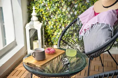 a glass table with a cup and a tray of donuts on a porch at Cozy Dubai Marina Design Studio close to Jumeirah Beach, Mall & Metro in Dubai