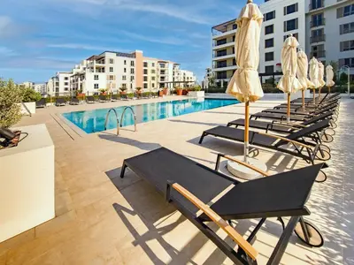 a row of lounge chairs with umbrellas next to a swimming pool at Splendid brand new 1BD apartment near the beach in Dubai