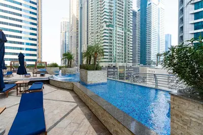 a large swimming pool with blue chairs and buildings at Vibrant - Prime Location Dubai Marina - Near Metro in Dubai