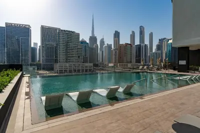 a swimming pool with chairs and a city skyline at Pristine 1 Bedroom - Business Bay in Dubai