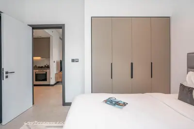 a bedroom with a white bed and a kitchen at Pristine 1 Bedroom - Business Bay in Dubai