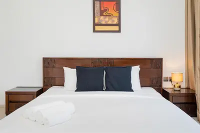 a bedroom with a large white bed with two tables at Comfortable 2 Bed - Near Marina Mall in Dubai
