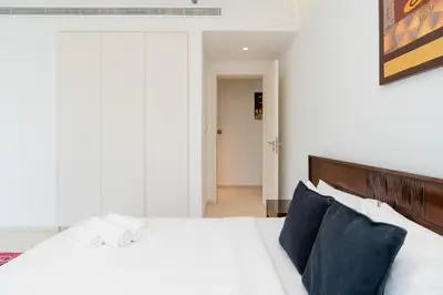 a bedroom with a white bed with blue pillows at Comfortable 2 Bed - Near Marina Mall in Dubai