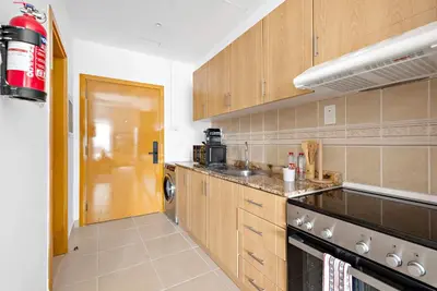 a kitchen with wooden cabinets and a stove top oven at Silkhaus New studio in Silicon Oasis ASB Tower in Dubai