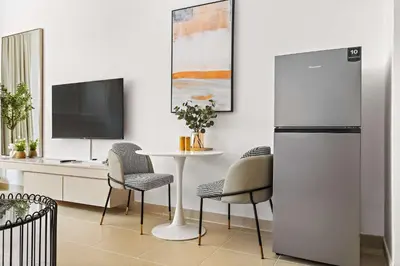 a kitchen with a table with chairs and a refrigerator at Silkhaus New Studio in ASB Tower Walking distance to mall in Dubai