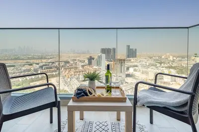 a balcony with two chairs and a table with a bottle of wine at Frank Porter - Bloom Heights in Dubai