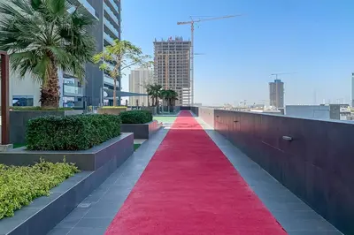 a red carpeted pathway in a city with buildings at Frank Porter - Bloom Heights in Dubai
