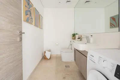 a white bathroom with two sinks and a toilet at Frank Porter - The Sterling by Omniyat in Dubai