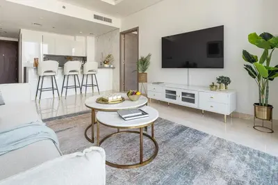 a living room with a couch and a tv and a table at Frank Porter - The Sterling by Omniyat in Dubai
