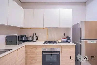 a kitchen with white cabinets and a stove top oven at Luxe - Relax in Style Scandi 1BR with Sofa Bed in Dubai