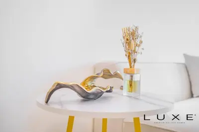 a white table with a gold console and a bottle of perfume at Luxe - Relax in Style Scandi 1BR with Sofa Bed in Dubai