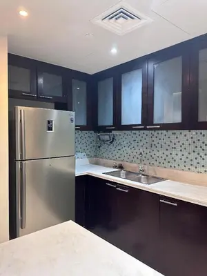 a kitchen with a stainless steel refrigerator and black cabinets at The Sand Castle - Ubora Residence Tower, Business Bay, Burj Khalifa View in Dubai