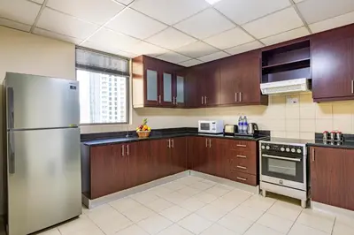 a kitchen with wooden cabinets and a stainless steel refrigerator at Roda Amwaj Suites Jumeirah Beach Residence in Dubai