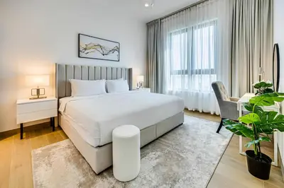 a bedroom with a large white bed and a chair at Amazing 1 bedroom in Port De La Mer near the sea in Dubai