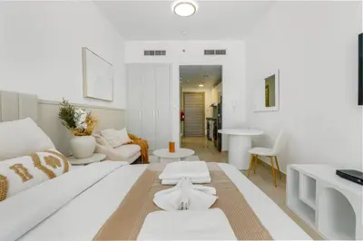 a white living room with a couch and a table at Bloom Height - Amazing Pool - Good Wi-Fi in Dubai