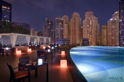 a swimming pool with tables and chairs and a city skyline at Overlooking Marina Views Next to Marina Mall 1BR Unit, The Address Residences, Dubai Marina by Deluxe Holiday Homes in Dubai