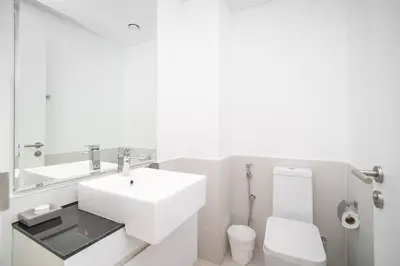 a white bathroom with a sink and a toilet at StoneTree - Furnished 2BR with floor-to-ceiling window in Dubai