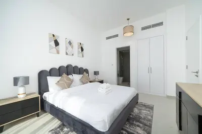 a white bedroom with a large bed and a bathroom at StoneTree - Furnished 2BR with floor-to-ceiling window in Dubai