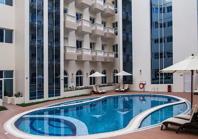 a swimming pool in the courtyard of a hotel at Lovely Studio Apartment in Hanover Square, JVC in Dubai