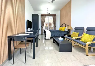 a living room with a couch and a table in it at Lovely Studio Apartment in Hanover Square, JVC in Dubai